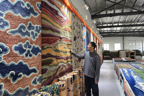 11月5日,貢保扎西介紹該公司生產的不同款式的現代藏毯。(中新社記者 丁思 攝)