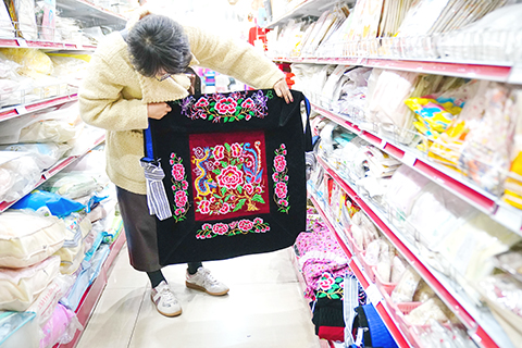 12月2日,年輕顧客在長春百貨商店挑選背孩子的老式綉花背被。(中新社記者 劉冉陽 攝)