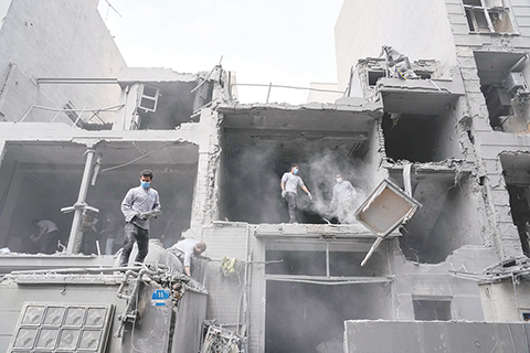 ◎ 三月十五日,伊朗德黑蘭,志願者們正在清理一座居民樓的殘骸。上周五,美以空襲襲擊了附近的一個警察局。(美聯社圖片/Vahid Salemi)